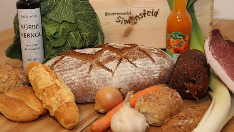 Bunt gemischtes Sortiment, © Josef Popp Verschiedene Lebensmittel wie Brot, Gemüse, Öl und Wurst auf einem Tisch.