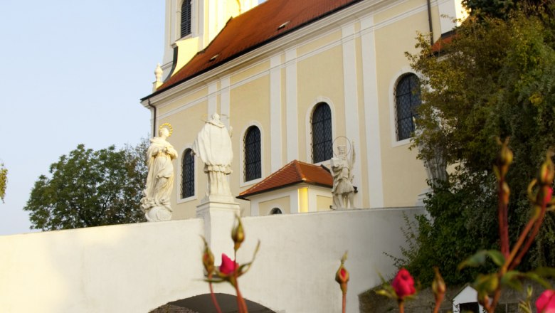 Pfarrkirche Wolkersdorf, © Fotostudio Semrad Pfarrkirche Wolkersdorf mit Statuen und Rosen im Vordergrund.
