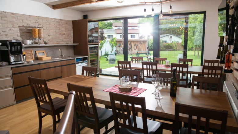 Winery Küssler, © Winzerhof Küssler Dining room with wooden table, chairs and view of the garden through large windows.
