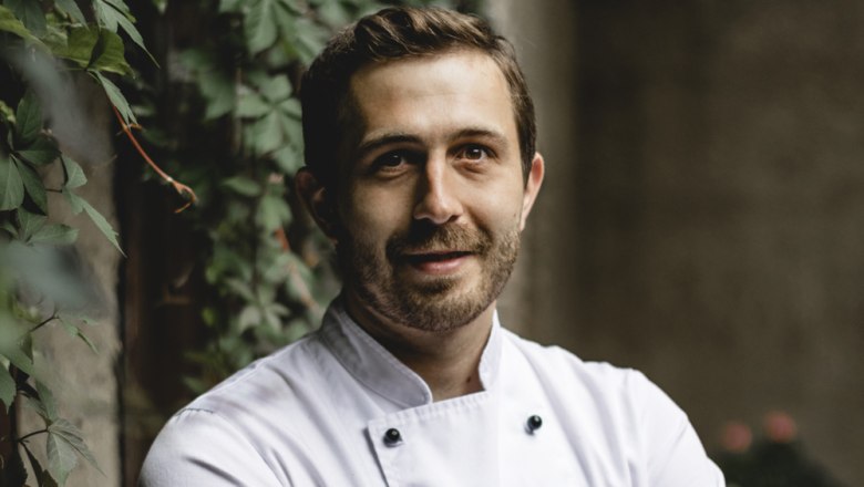 Stefan Fritsch pays attention to the high quality of the food, © Niederösterreich Werbung/David Schreiber A man in a white chef's jacket stands in front of a wall overgrown with ivy.