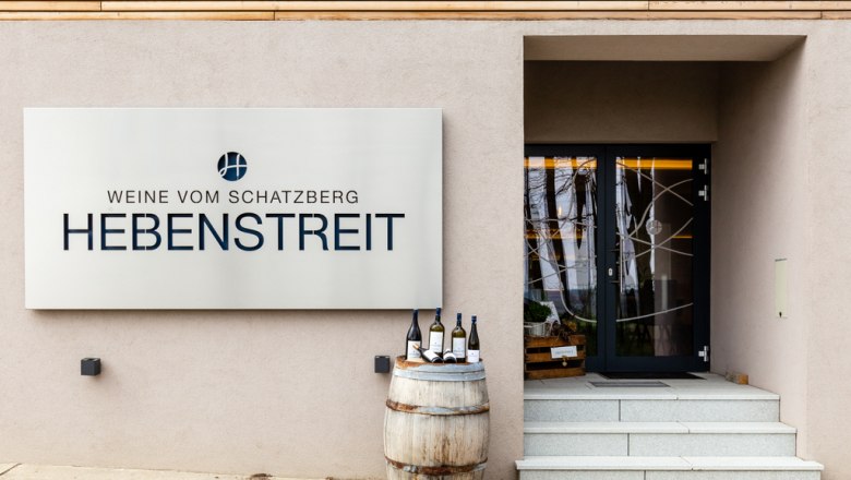 Willkommen im Weingut Hebenstreit, © A. Schweighofer Eingang zu Hebenstreit Weine mit Schild und Weinfass.