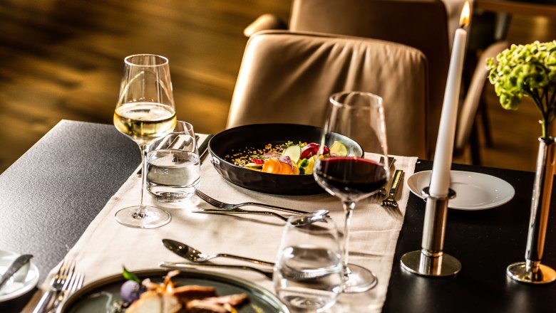Restaurant im Hotel der Therme Laa, © Therme Laa Eleganter Restauranttisch mit Weingläsern, Kerze und Gourmetgerichten.