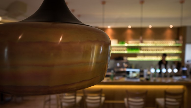 Moravian Embassy, © tonality Close-up of a lamp in a stylish café with a bar in the background.