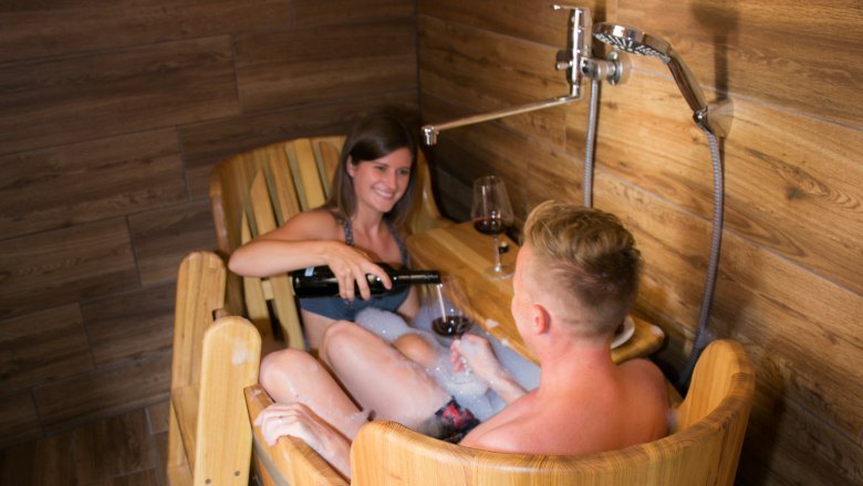 Winery Küssler, © Winzerhof Küssler Two people in a wooden tub shower with wine.