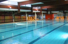 Sportbecken, Erholungszentrum Stockerau, © Stadtgemeinde Stockerau Innenansicht eines Schwimmbads mit leeren Liegestühlen am Beckenrand.