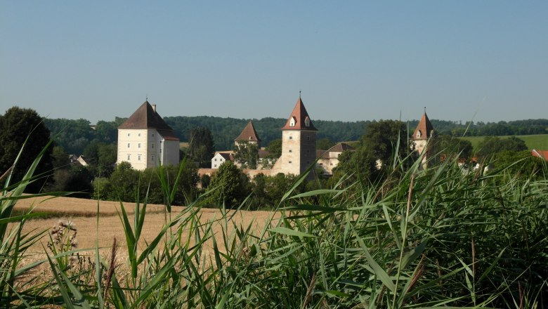 Großmugl, © Gemeinde Großmugl Schloss mit Türmen hinter einem Feld und hohen Gräsern.