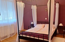 Heimelige Schlafzimmer, © Fam. Windisch Schlafzimmer mit Himmelbett, lila Wänden und weißen Vorhängen.