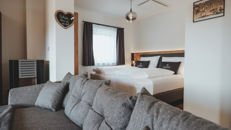 Gemütliche und hochwertige Einrichtung, © Chalaalets Modern eingerichtetes Schlafzimmer mit grauem Sofa und Doppelbett.