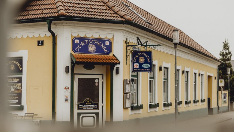 Dorfschenke in Oberzögersdorf, © Niederösterreich Werbung/Sophie Menegaldo Gelbes Gasthaus mit Schild 'Dorfschenke', traditionelles Ambiente.