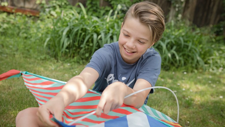 Child at play, © Weinviertel Tourismus GmbH / Lahofer A child sits in the grass holding a colorful kite.