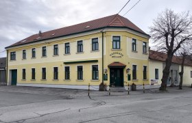 Gasthaus Müller, © Weinviertel Tourismus Gelbes zweistöckiges Gebäude mit der Aufschrift 'Gasthaus Müller'.