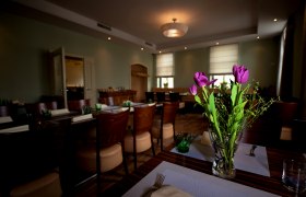 Mährische Botschaft, © tonality Ein stilvoll eingerichteter Raum mit gedeckten Tischen und einem Blumenstrauß aus lila Tulpen im Vordergrund.