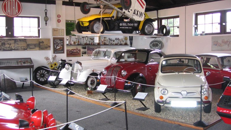 Classic car museum Poysdorf, © Oldtimermuseum Poysdorf Interior view of a classic car museum with various classic cars and an airplane on the ceiling.