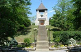 Aussichtswarte am Hutsaulberg, © Berger Steinturm auf einem Hügel mit Treppe und grüner Umgebung.