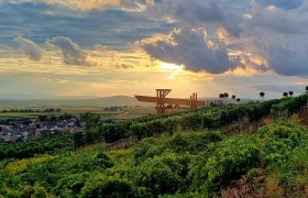 Weinblickterrasse, © Gemeinde Russbach Weinberge bei Sonnenuntergang mit moderner Terrasse im Hintergrund.