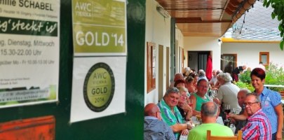 Buschenschank Schabel, © Familie Schabel Menschen sitzen an einem langen Tisch in einem überdachten Außenbereich eines Restaurants.
