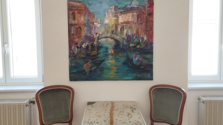 the MERKIMA Gallery, © Doris Hauser Two chairs and a table in front of a painting on a white wall.