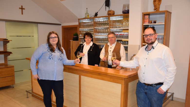 Familie Piller, © Familie Piller Vier Personen stehen an einer Theke und halten Weingläser in der Hand.