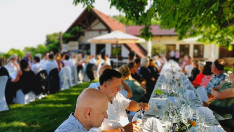 Tafeln im Weinviertel, © Weinstraße Weinviertel Menschen sitzen an langen, gedeckten Tischen im Freien bei einer Veranstaltung.