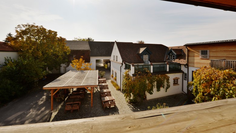 Weingut, © Zuschmann-Schöfmann Innenhof eines Weinguts mit Holzbauten und Weinreben.