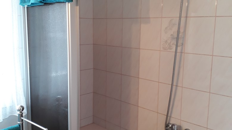 Badezimmer, © Barbara Muck Badezimmer mit Badewanne, Duschvorhang und blauen Handtüchern.