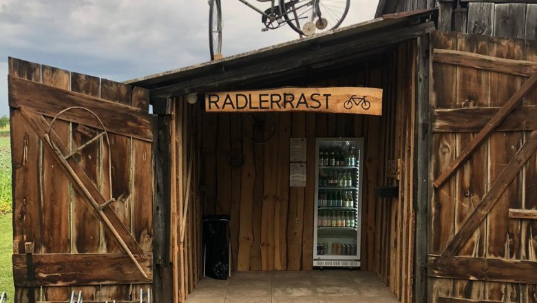 Pottenhofen cyclists' rest stop, © Lukas Cermak Wooden hut with 'Radlerrast' sign, bicycle on the roof, drinks inside.