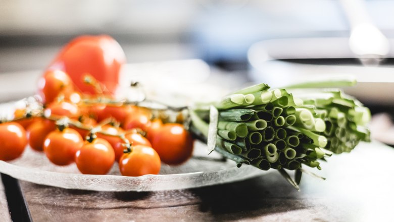 Produkte stammen von umliegender Landwirtschaft, © Niederösterreich Werbung/David Schreiber Nahaufnahme von frischen Kirschtomaten und Frühlingszwiebeln auf einem Teller.