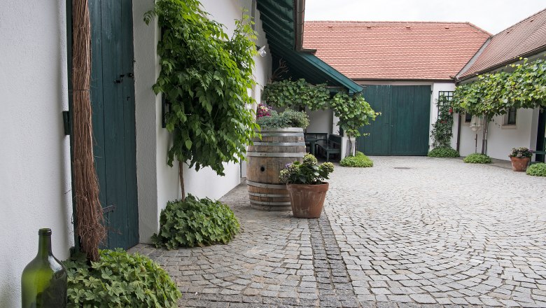Schöner Winzerhof, © Erich Marschik Innenhof eines Winzerhofs mit Kopfsteinpflaster, grünen Türen und Pflanzen.