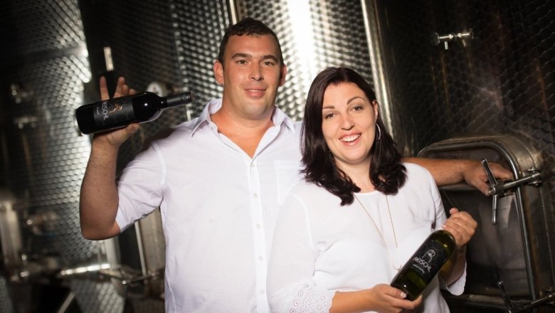 Klemens and Marion Reischl, © Bernhard Raab A winemaker couple in the wine cellar with bottles of wine in their hands.