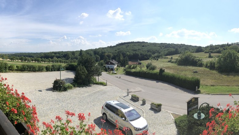 Weitblick, © Hotel Stich Panoramablick von einem Hotelbalkon auf eine ländliche Landschaft mit Hügeln und Wiesen.