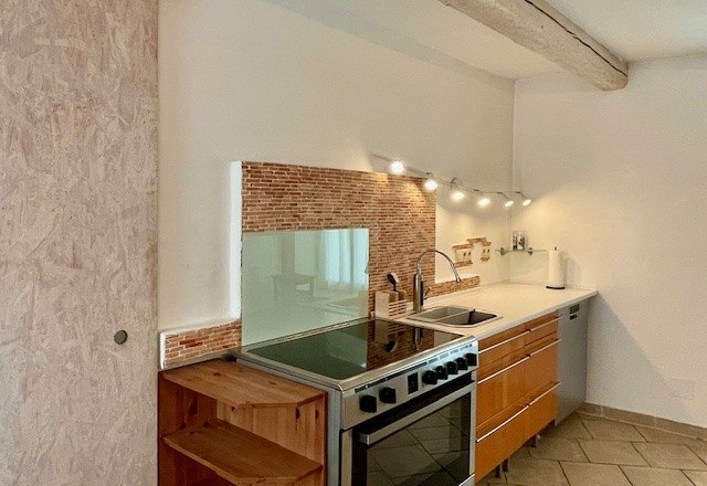 Küche, © Julia Grünschachner Moderne Küche mit Holzschränken, Herd, Spüle und Fliesenrückwand.