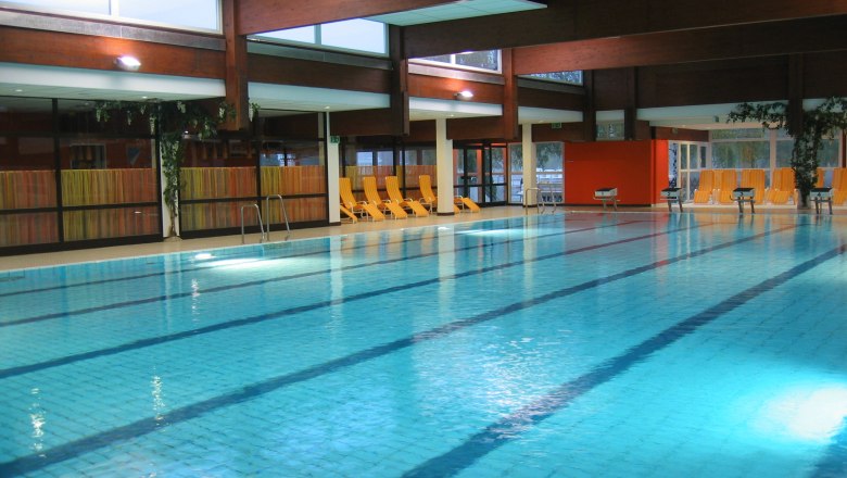 Sportbecken, Erholungszentrum Stockerau, © Stadtgemeinde Stockerau Innenansicht eines Schwimmbads mit leeren Liegestühlen am Beckenrand.