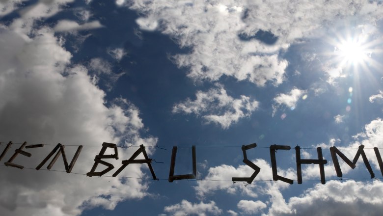 Weinbau Schmid, © Rainer Schmid Holzschriftzug 'Weinbau Schmid' vor bewölktem Himmel und Sonne.