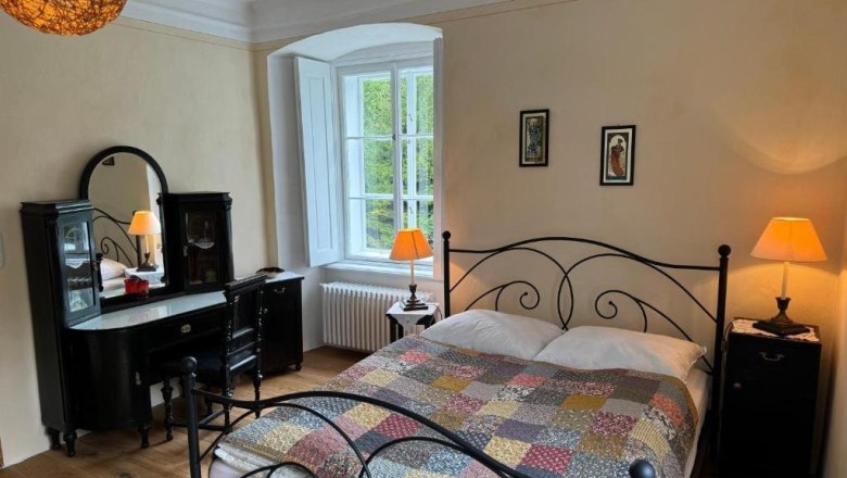 Gästezimmer, © Andrea Schubert Gemütliches Gästezimmer mit Doppelbett, antikem Schminktisch und warmem Licht.