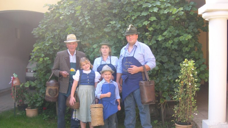 Familie Graf, © Johannes Graf Familie in traditioneller Kleidung vor einem Weinstock.