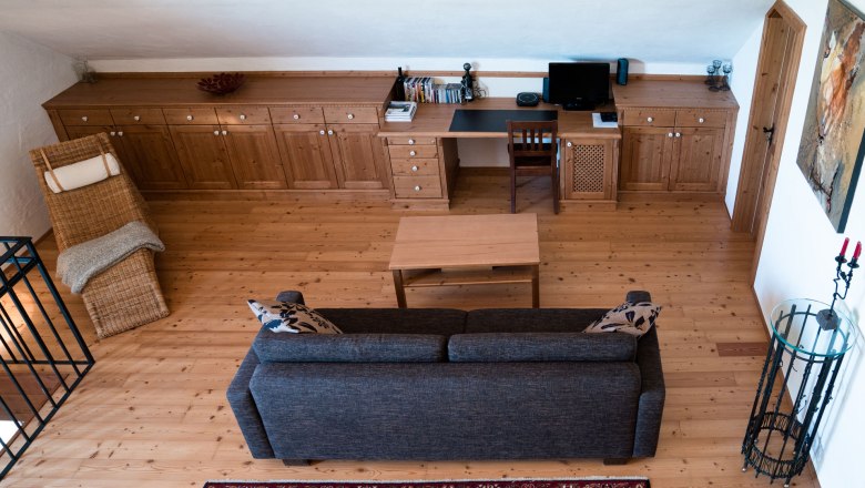 Obergeschoss, © Weinakademie Retz Wohnzimmer im Obergeschoss mit Holzboden, Sofa, Tisch, Schreibtisch und Stuhl.