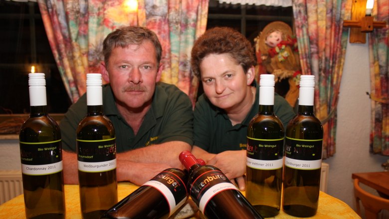 Weingut Altenburger, © Fam. Altenburger Zwei Personen hinter einem Tisch mit Weinflaschen.