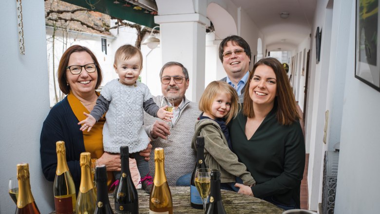 Familie Hugl, © Robert Herbst Familie sitzt an einem Tisch mit Sektflaschen und Gläsern.