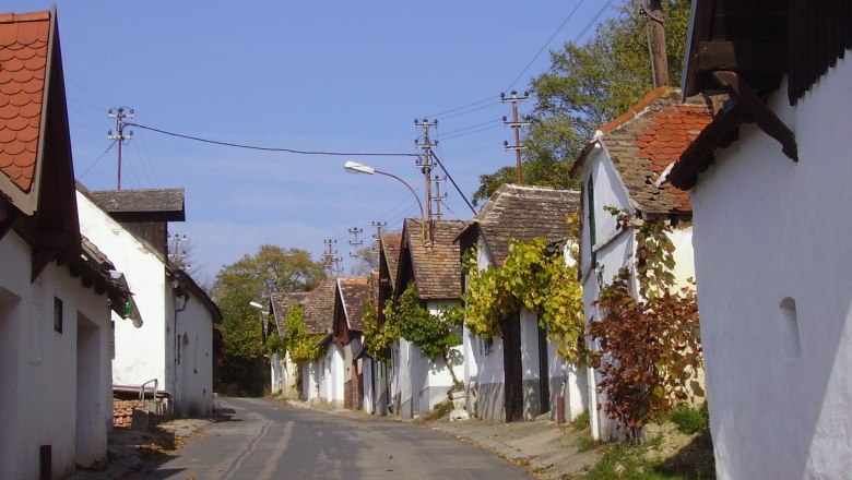 Große Kellertrift, © Andrea Kitla Eine schmale Straße mit traditionellen, weißen Häusern und Weinreben an den Fassaden.
