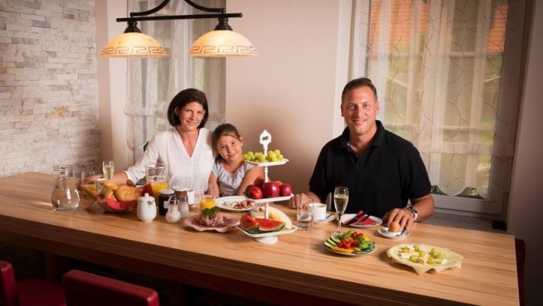 Delicious snack, © Bernhard Raab Family having breakfast at a wooden table with fruit and drinks.