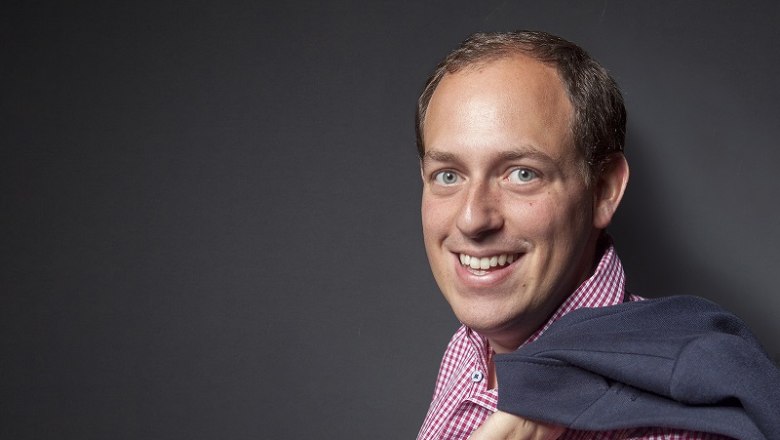 Weingut Gilg, © Alexander Seidl Mann in kariertem Hemd mit Jacke über der Schulter vor grauem Hintergrund.