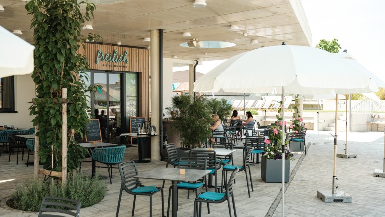 freilich Außenbereich, © Michael Reidinger Außenbereich eines Cafés mit Tischen, Stühlen und Sonnenschirmen.