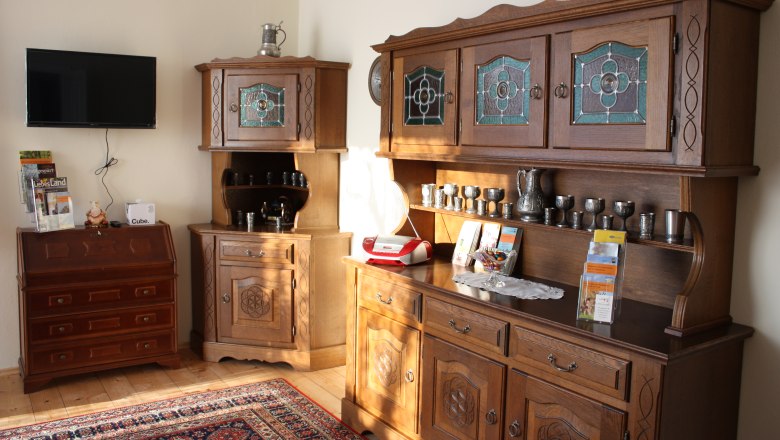Living room, © Majewsky Zant Living room with antique wooden furniture, a TV on the wall and decorative metal vessels.