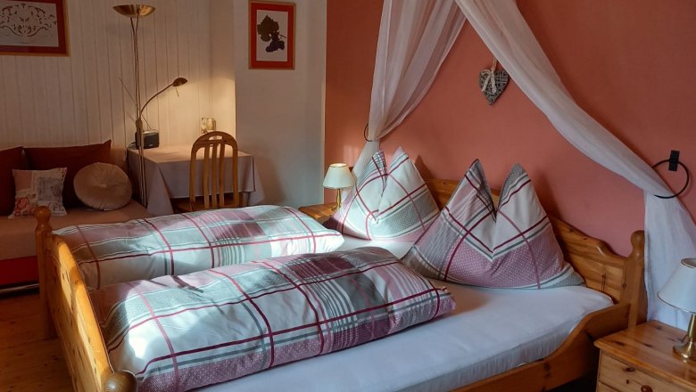 Gästezimmer, © Familie Fleischmann Gemütliches Gästezimmer mit Doppelbett, Nachttischlampen und Schreibtisch.