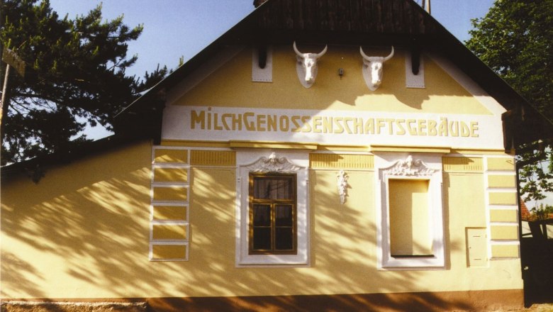 Ketzelsdorfer Milchkammer, © Christian Mock Ein gelbes Gebäude mit der Aufschrift 'Milchgenossenschaftsgebäude' und zwei Stierschädeln an der Fassade.