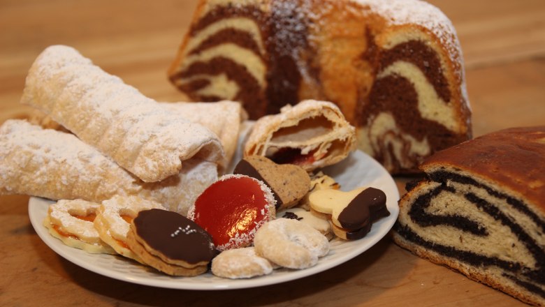 Köstliche Mehlspeisen, © Josef Popp Verschiedene Gebäcksorten auf einem Teller, darunter Kekse, Strudel und Marmorkuchen.