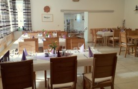 Heurigenlokal, © Familie Piller Innenansicht eines gemütlichen Heurigenlokals mit gedeckten Tischen und Holzmöbeln.