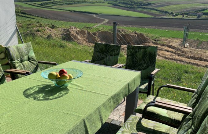 Terrace with a view of the garden, © Reinhard Gurschka Terrace with green table and chairs, view of fields and hills.