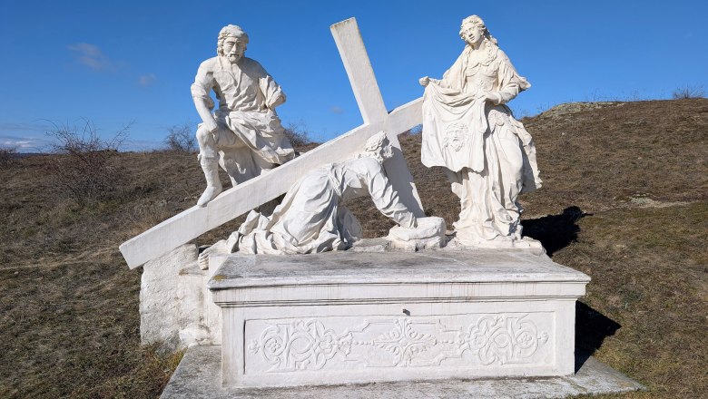 Kalvarienberg, © Retzer Land / Daniel Wöhrer Steinskulptur einer religiösen Szene mit drei Figuren und einem Kreuz auf einem Hügel.