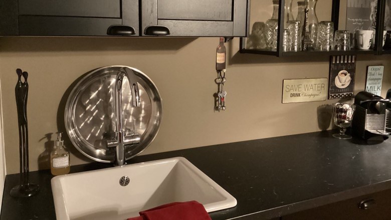 Küchenzeile, © Weitschacher Moderne Küchenzeile mit Spüle, schwarzem Schrank, Regalen mit Gläsern und Kaffeemaschine.